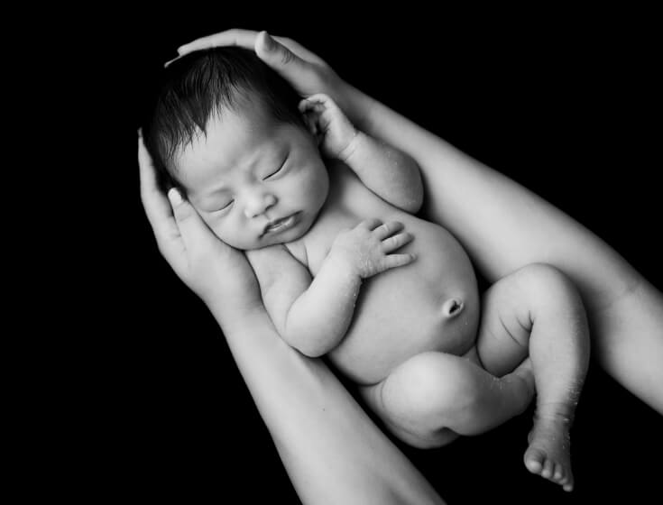 モノクロ写真の母の腕に抱かれた新生児